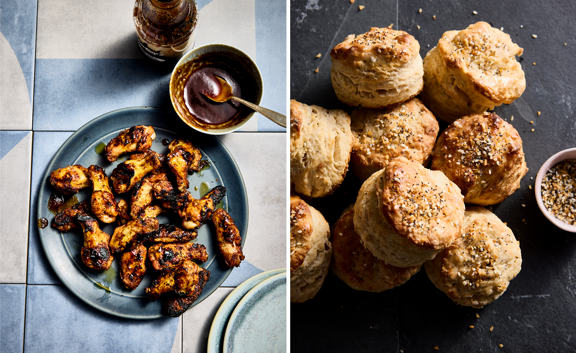 A plate of grilled chicken wings with a small bowl of dipping sauce, next to a glass beverage, on a tiled table; and a pile of baked biscuits sprinkled with seasoning on a dark surface.