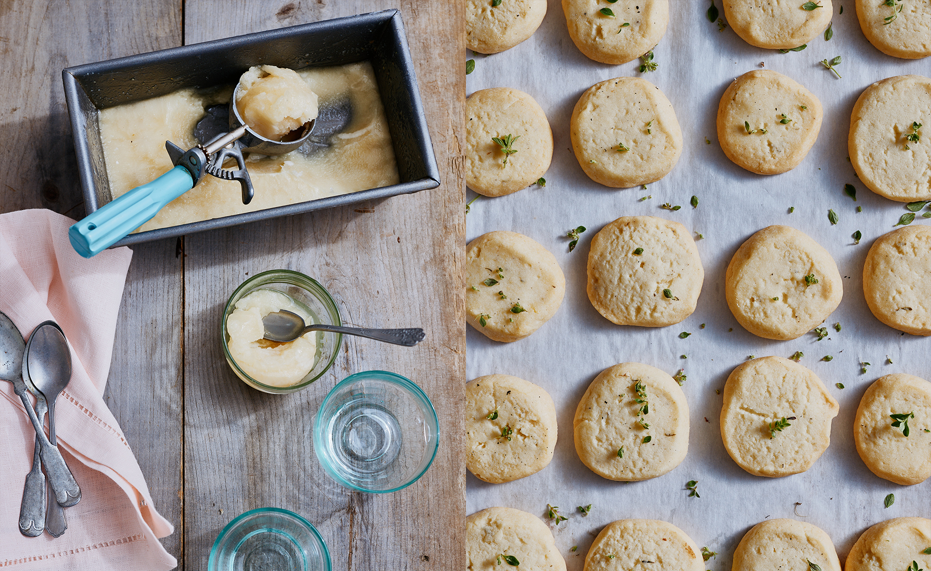 Sorbet being scooped from a pan, small spoons, and glasses on a rustic wooden table. To the right, freshly baked cheese cookies with herbs on a baking sheet.