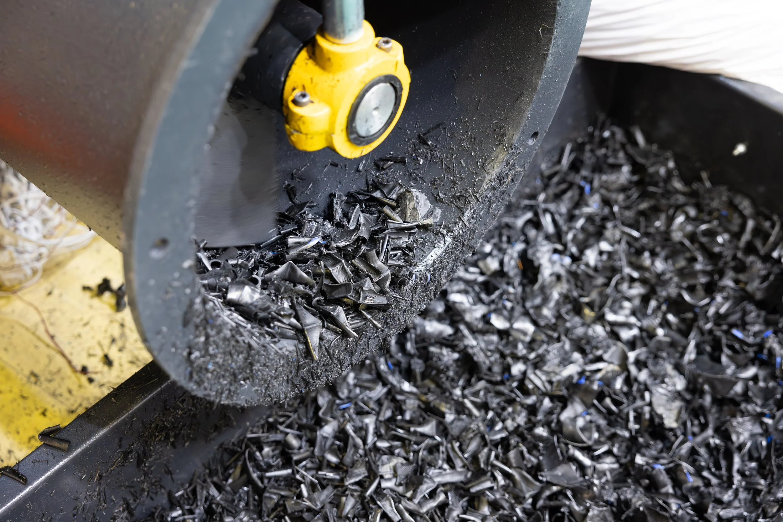 black shards of plastics being grinded down through machine