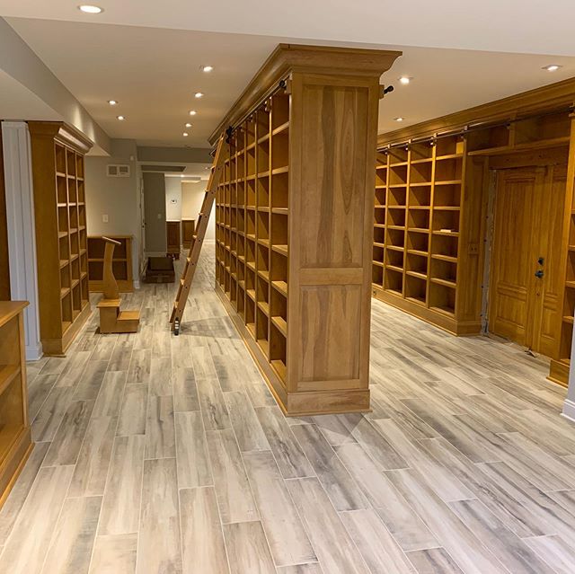 Pictures of a #homelibrary project with 55 floor-to-ceiling #bookcase units for over 970 feet of #bookshelf space with rolling #libraryladder and #raisedpanel details.  #library