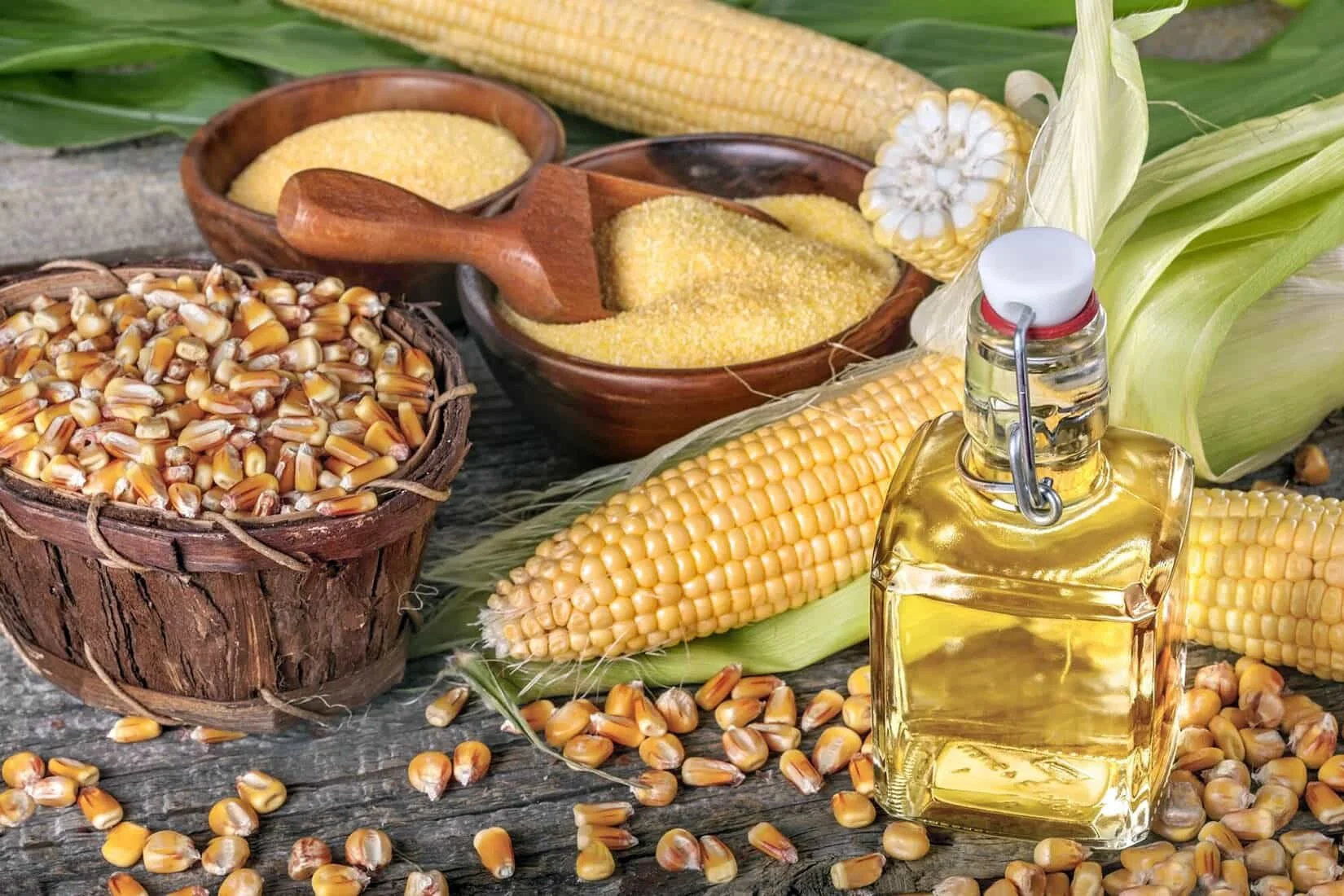 corn oil and dried corn kernels on a wooden table