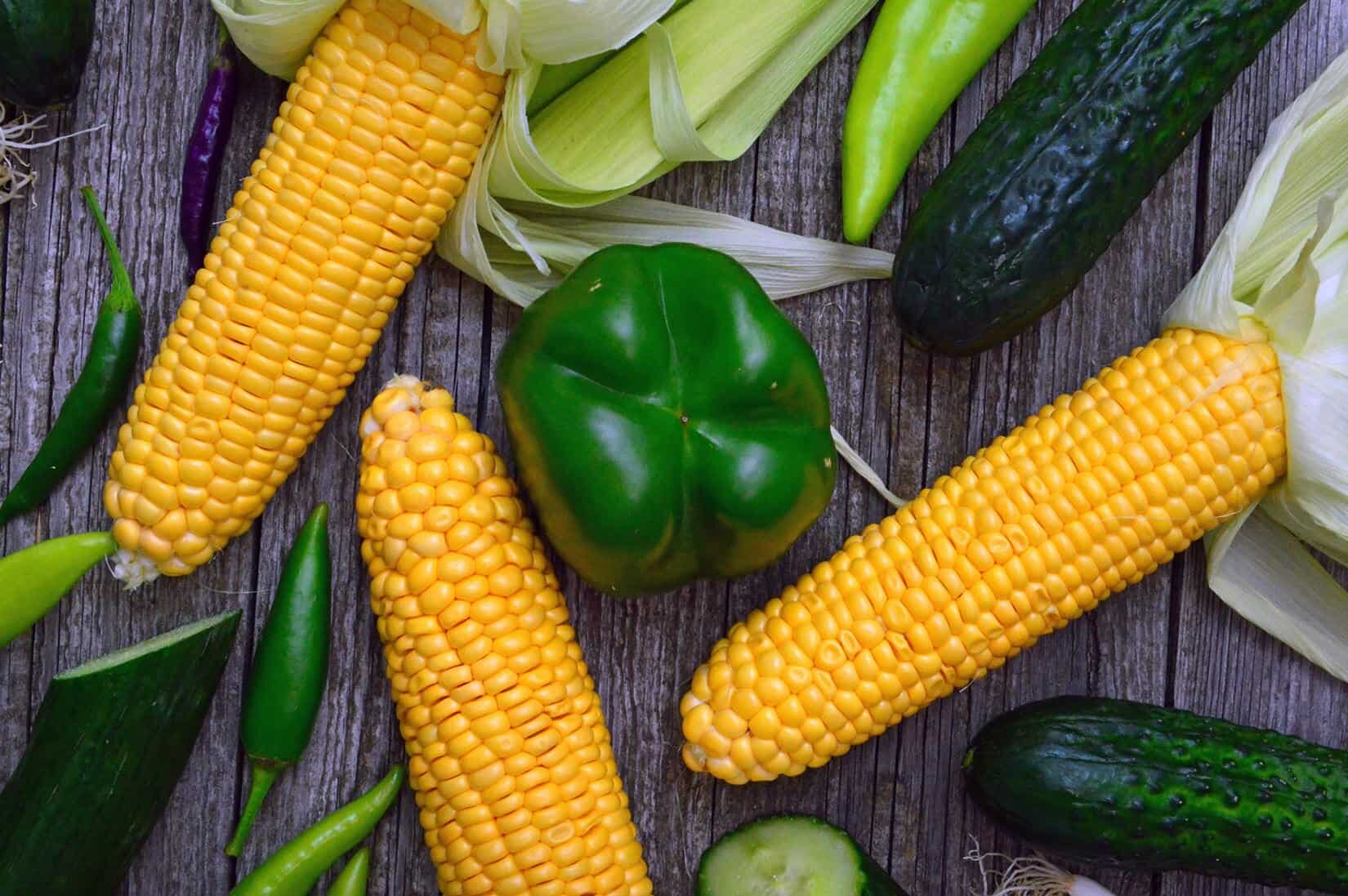 corn on the cob and green peppers on a table