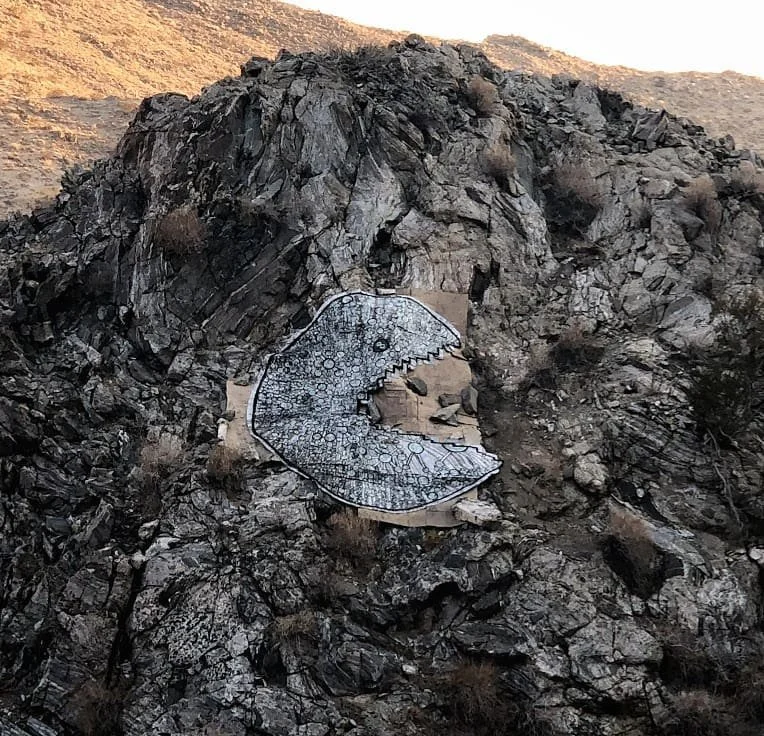 Large-scale moth-shaped land art installation on a rocky hillside by Calvin Brett