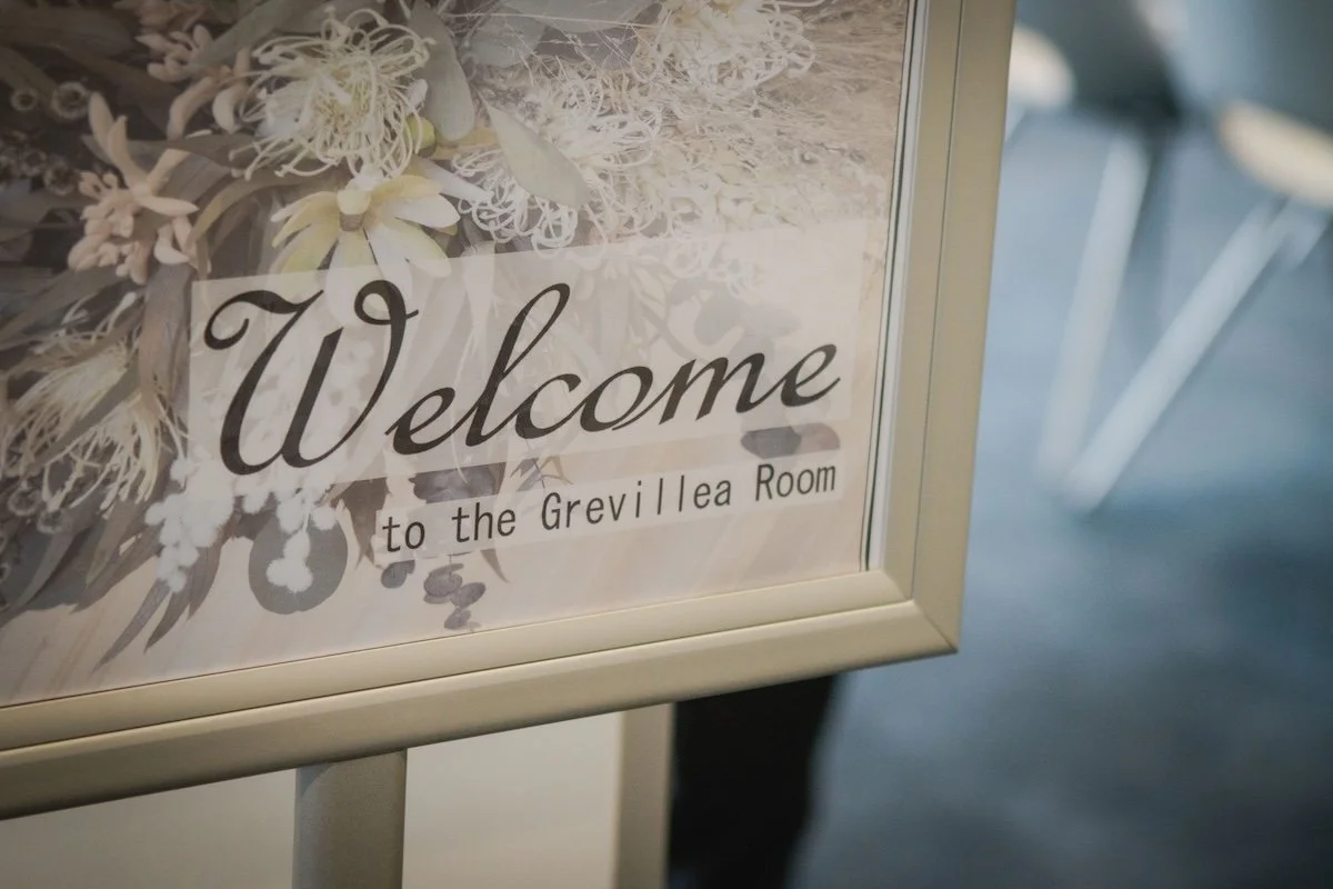A sign reads 'Welcome to the Grevillea Room' with a floral design background.