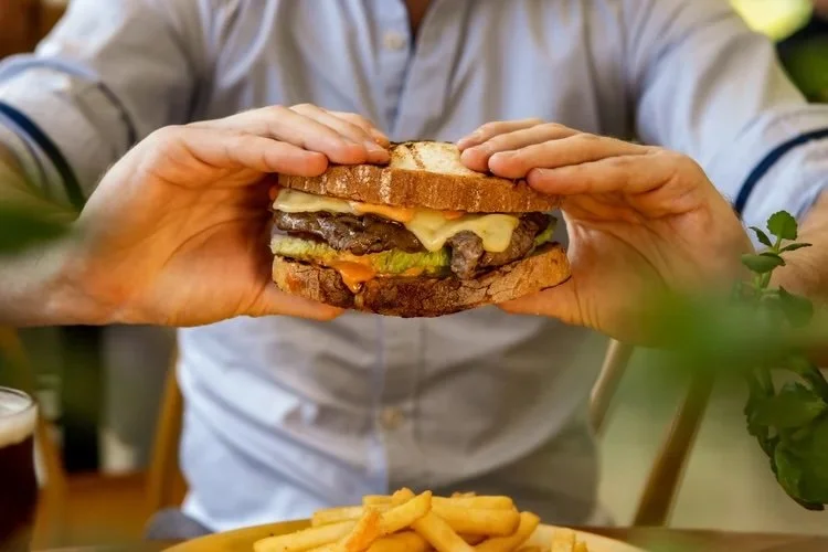 A man holding a steak sandwich that looks appetising