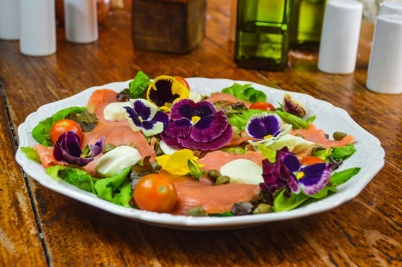 Salada de salmão com amor-perfeito, tomates cereja, alcaparras, folhas verdes e queijo de búfala da @fornellonepízzaria