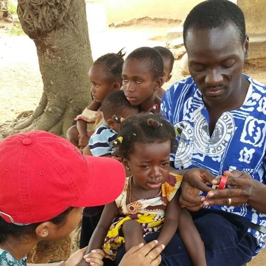 Adam Sandow still finds time to work in his field of Nutrition. Here he is working with a volunteer to measure a child for clinical malnourishment during the Point Hope Community Nutrition Outreach project done periodically in villages throughout the Central Region in Ghana.