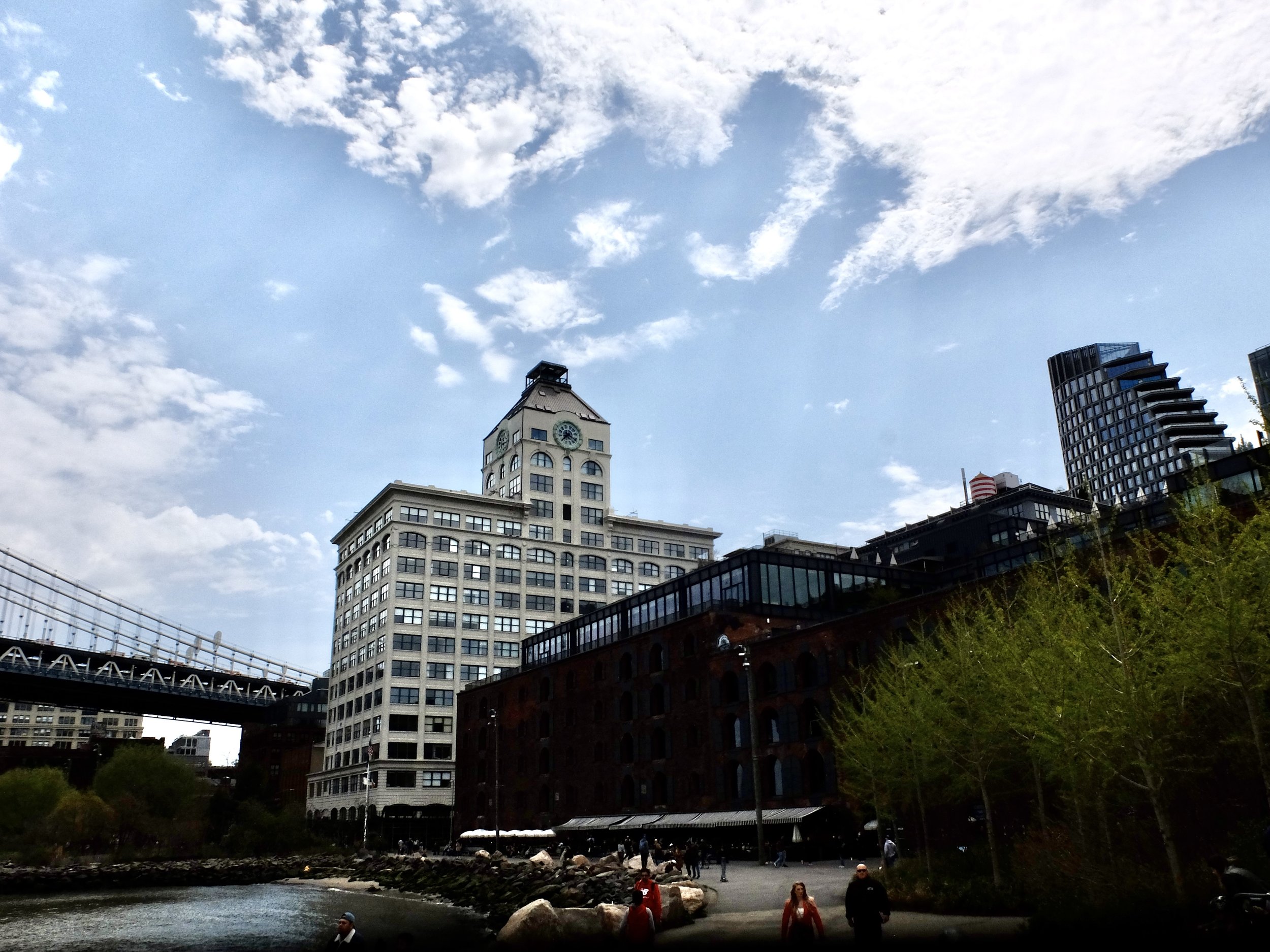  DUMBO from the Brooklyn Bridge Park.  In front of the clock tower building, the big brown building is Empire Stores, a former warehouse complex now a food hall, shops &amp; restaurants.  We had lunch on the rooftop.  “After a fire demolished the ori