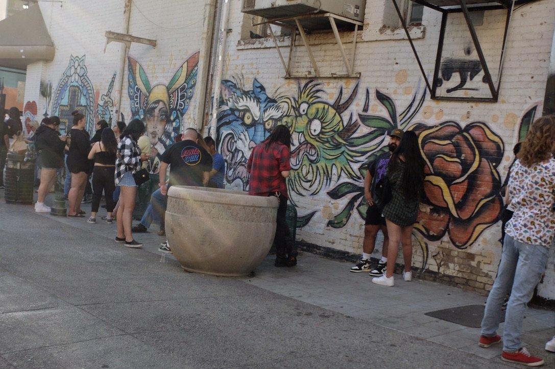 Folks lined up for a tattoo parlor