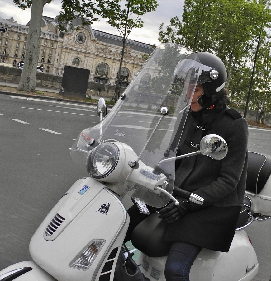 A cigarette just lit, a smart phone under the helmet, on a Vespa on Quai Francois MItterand, Paris, France.