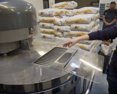  Checking the dough in a majorly big industrial-sized  mix master.  
