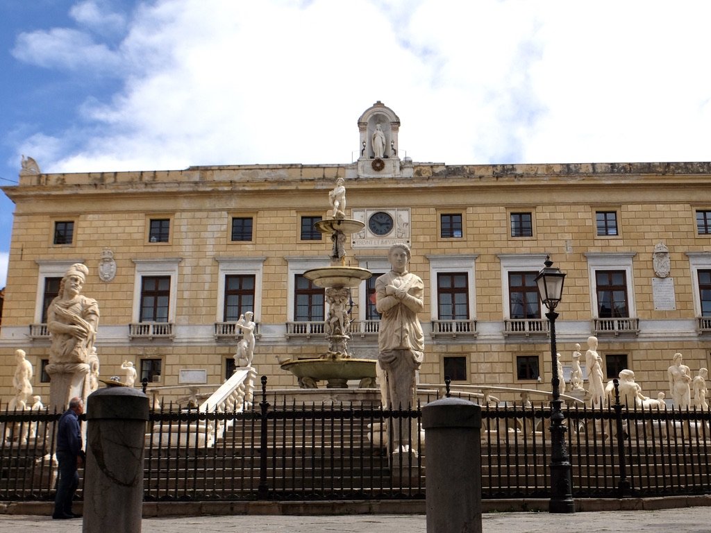  “The Praetorian Palace…it houses the mayor and the offices of the municipality of Palermo.”  In front is the Fontana Pretoria.  “Between 18th century and 19th century, the fountain was considered a sort of depiction of the corrupt municipality of Pa