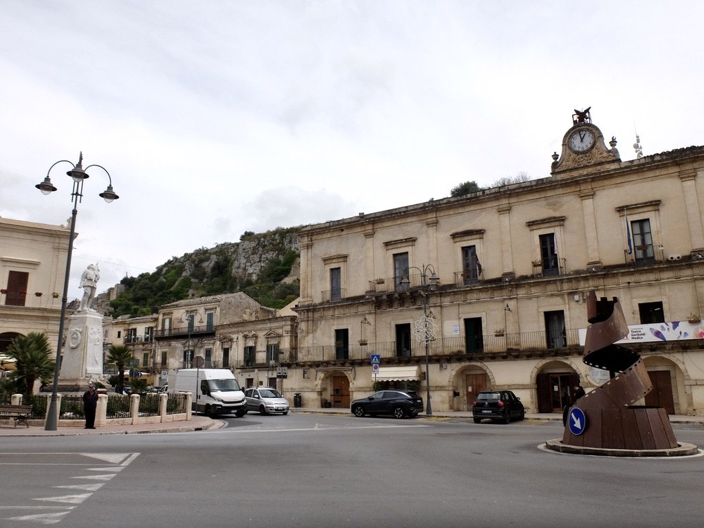  Modica’s main piazza with a WW II Memorial &amp; roundabout with a sculpture from a film festival of movies &amp; chocolate. 