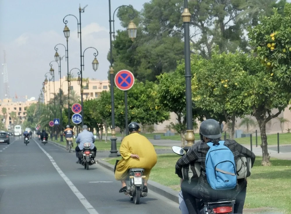 Leaving Marrakech.  The first motorcyclist is wearing his helmet backwards; we saw that a lot.  The billowing jdellaba is quite a sight.   