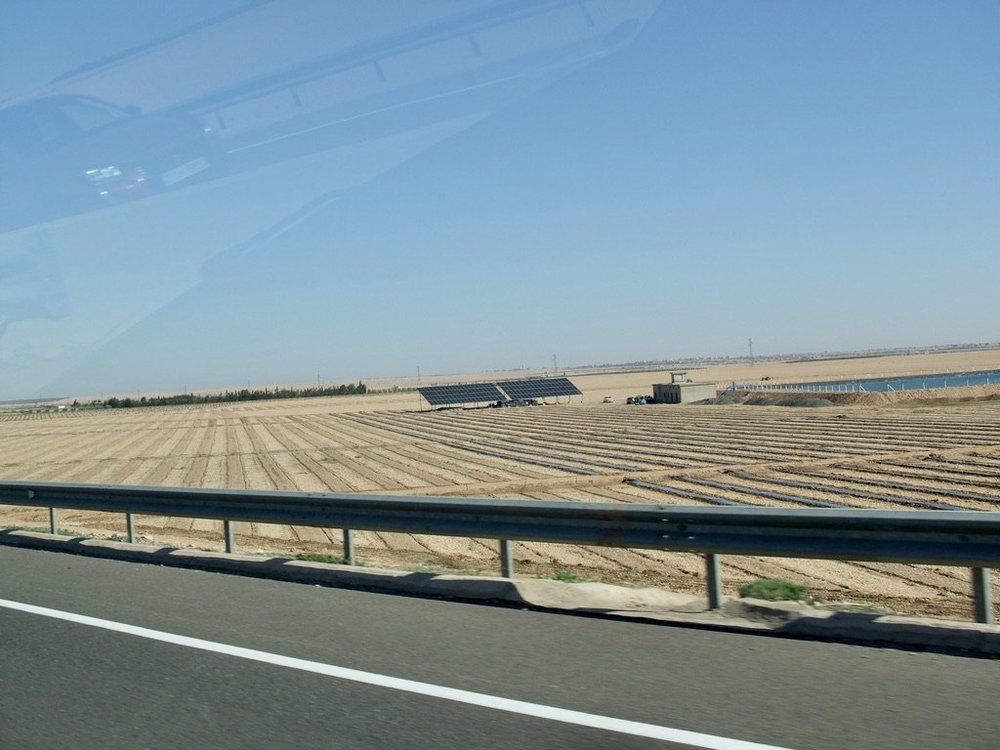  It is reminiscent of California’s US 5 going through the Central Valley.  The solar panels provide power for the pumps bringing up water. 