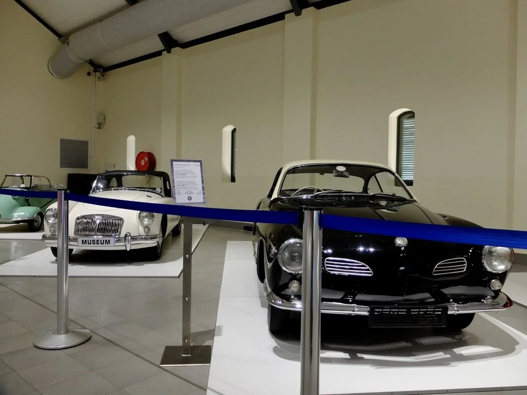  In the middle, a MGA similar to my red one.  On the right is a Karmann-Ghia.  Both Nomi &amp; I owned Karmann Ghias at one time.  Little green car on the left is adorable &amp; a featherweight.  One like that rolled over my foot in a crosswalk in 19