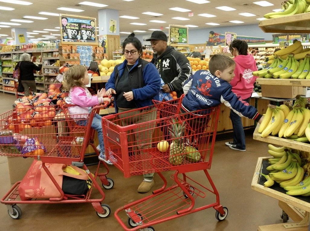  A family wearing NY paraphernalia, shopping at Trader Joe's Paramus, New Jersey.    This T.J.’s is huge but the largest one is Essex Crossing on the Lower East Side of Manhattan.   