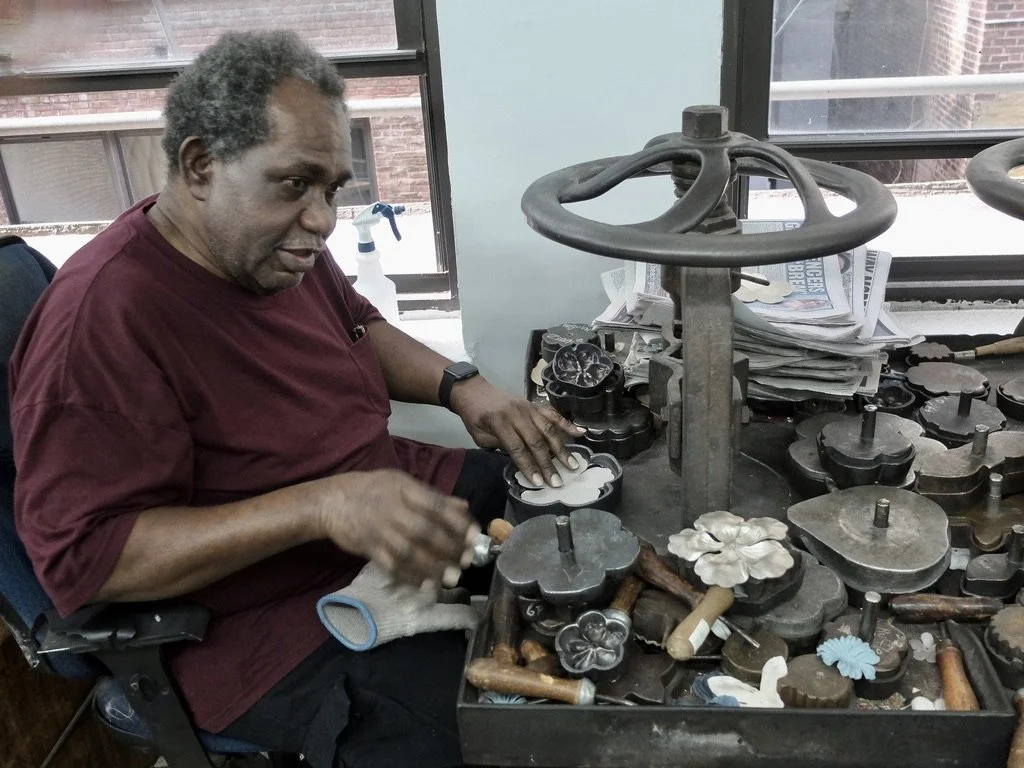  Al places the cut flower petals into the bottom half of the mold that he has warmed up.  He then places the top &amp; the whole mold goes into the press.  He said there used to be a coal fire under this table. 
