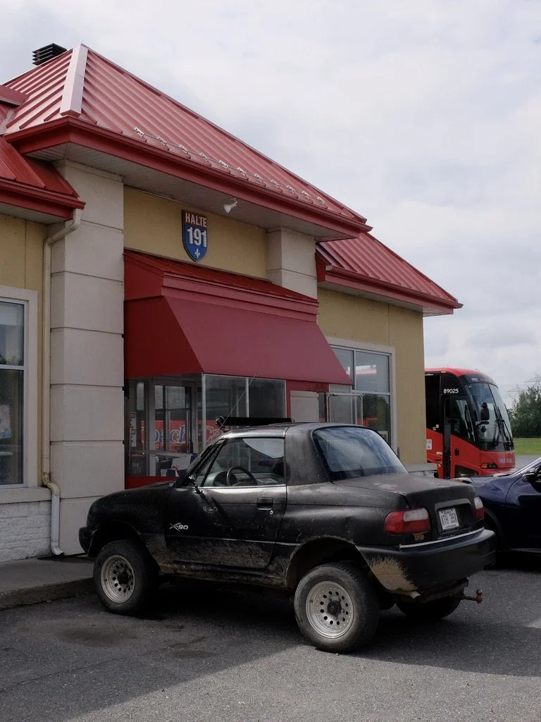     Suzuki X-90 at LE 4 Saisons rest stop.   That’s our bus peeking out next to the building.   