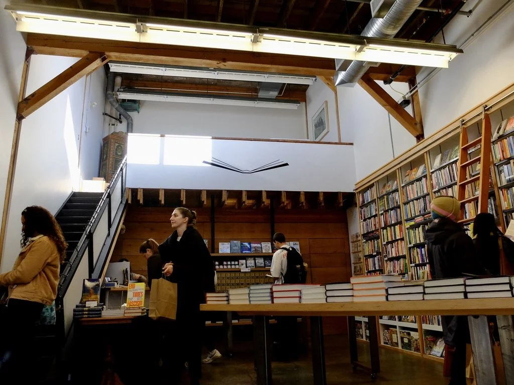  On Granville Island “Upstart &amp; Crow is a not-for-profit literary arts studio and bookstore that champions writers, readers and stories, and the role they play in shaping our lives.”  Above Nomi’s head was a shelf of banned books.   