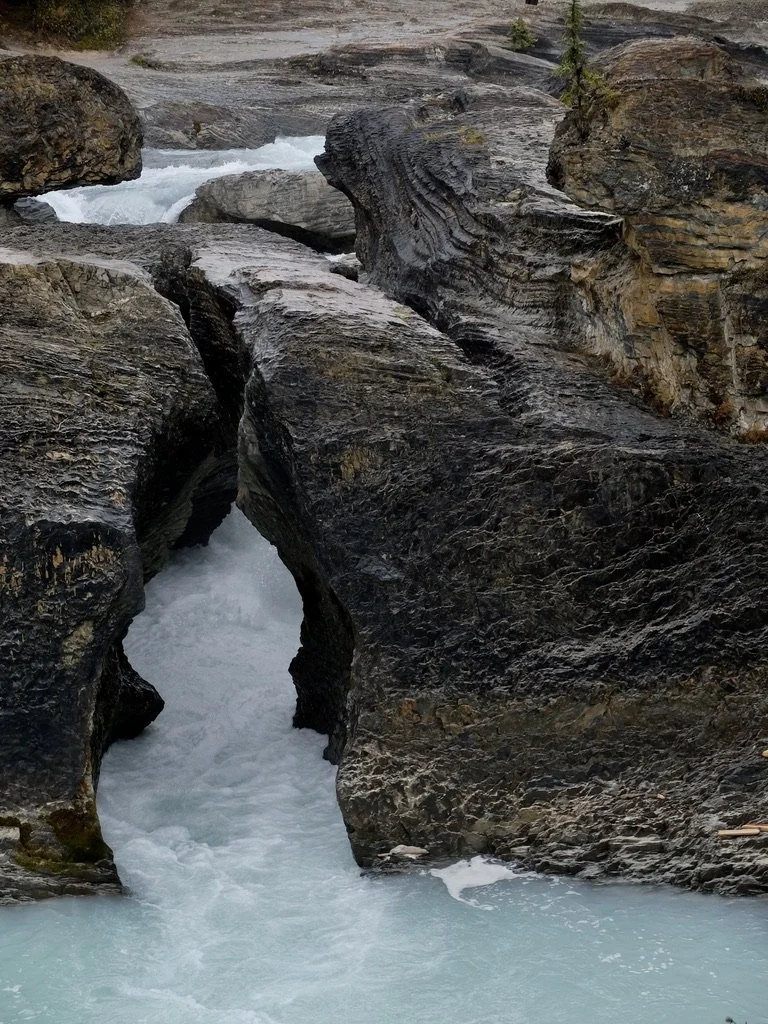  In Yoho Nat’l Park, B.C.,  “Natural Bridge is a dramatic rock formation created by thousands of years of erosion by the Kicking Horse River. Softer rock beneath a harder limestone band eroded more quickly, eventually diverting the river under the ro