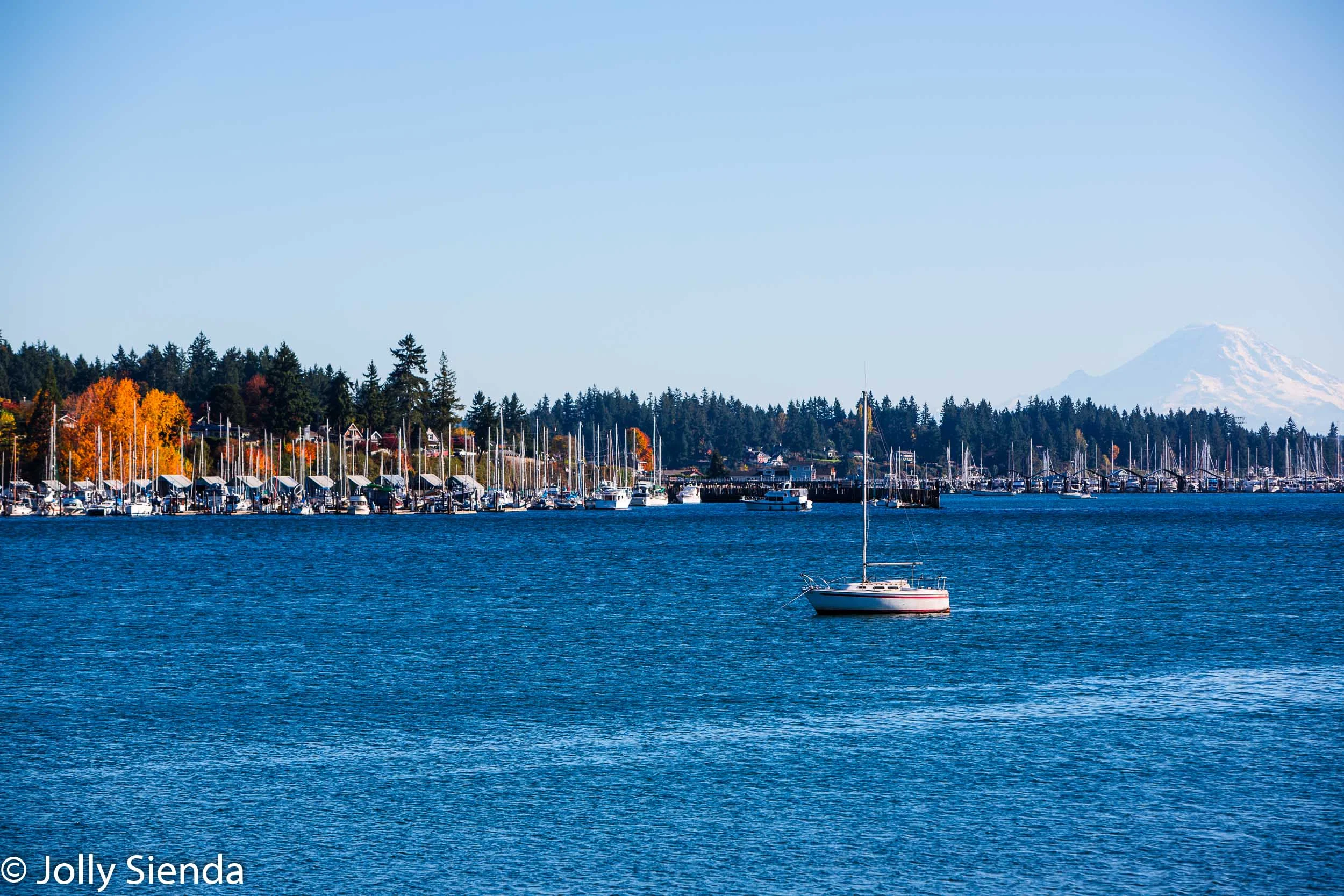 Mount Rainier looks over Liberty bay and a sailboat