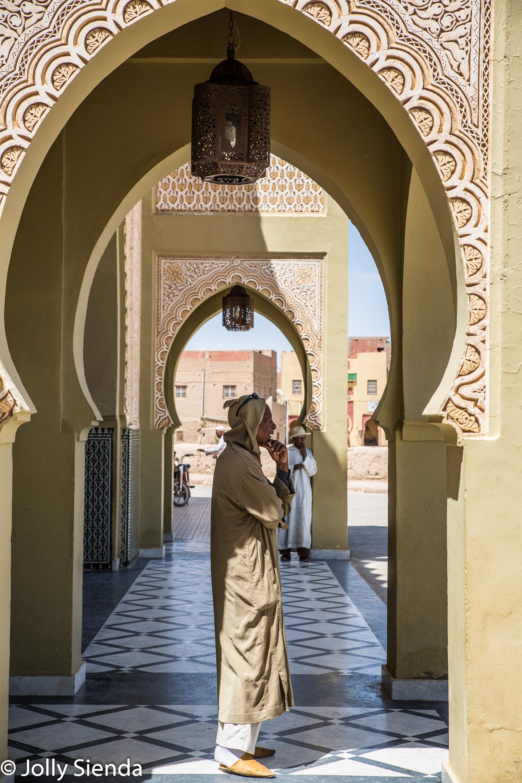Man wears jalaba under islamic archway