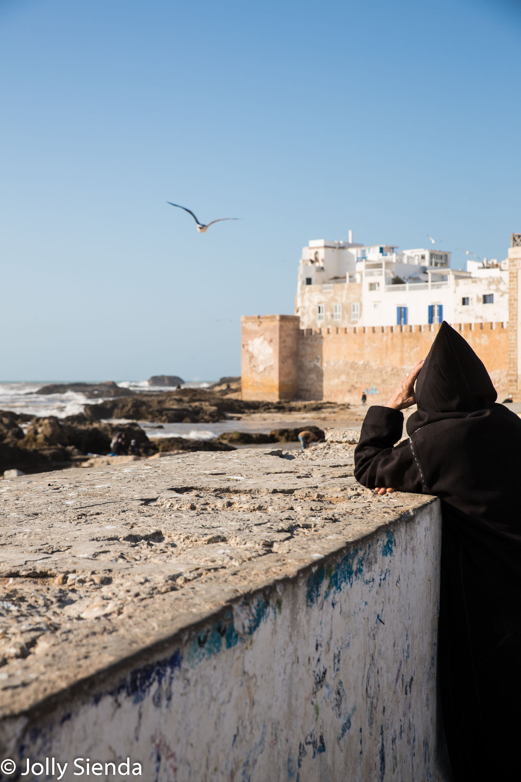 Man wears jabala and looks at the sea at Essaouira