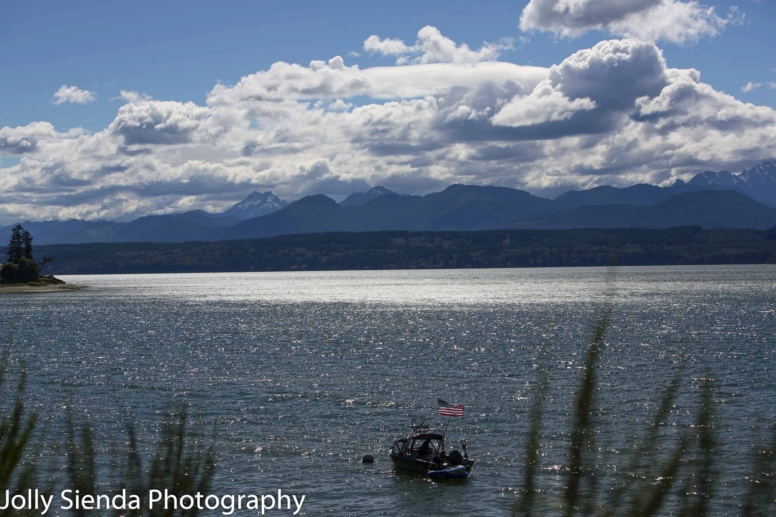 Boat with an American Flag on Hood Canal sailing towards the Olympic Mountains.