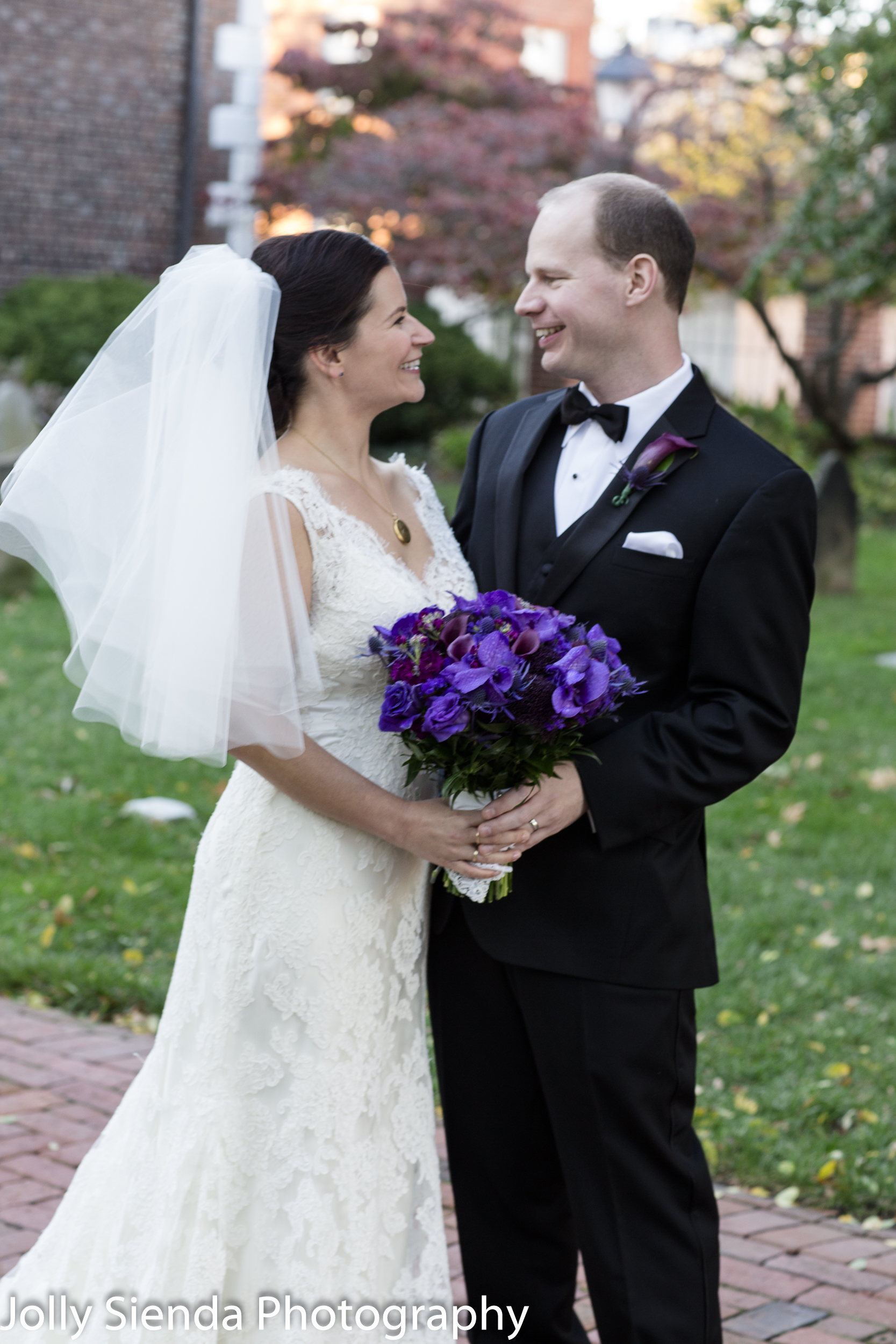Purple wedding bouquet and the bride and groom