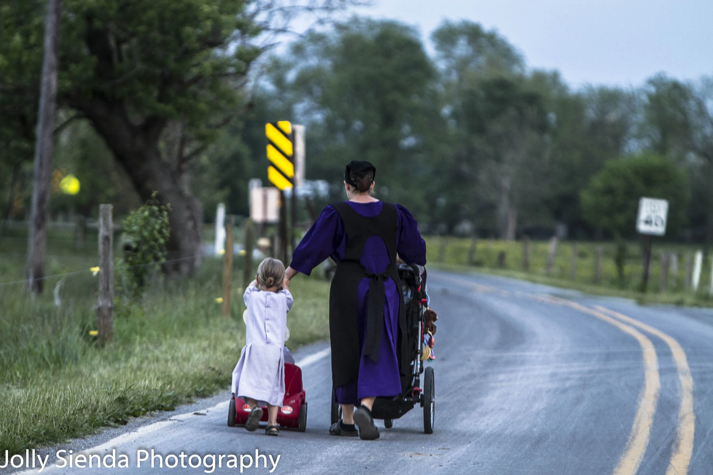 Amish mother pushes a baby carriage with her daughter