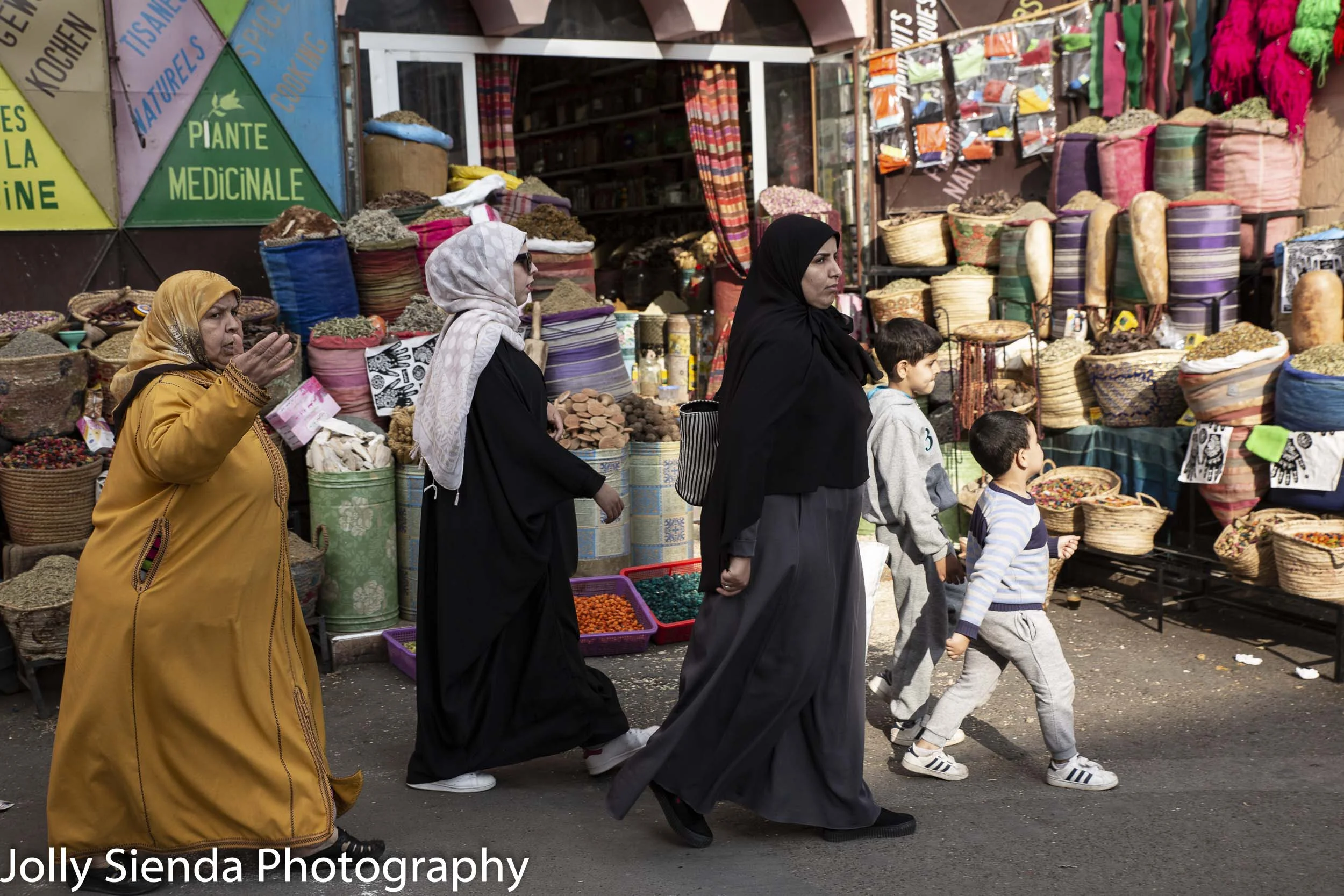 Moroccan people pass shopping stalls