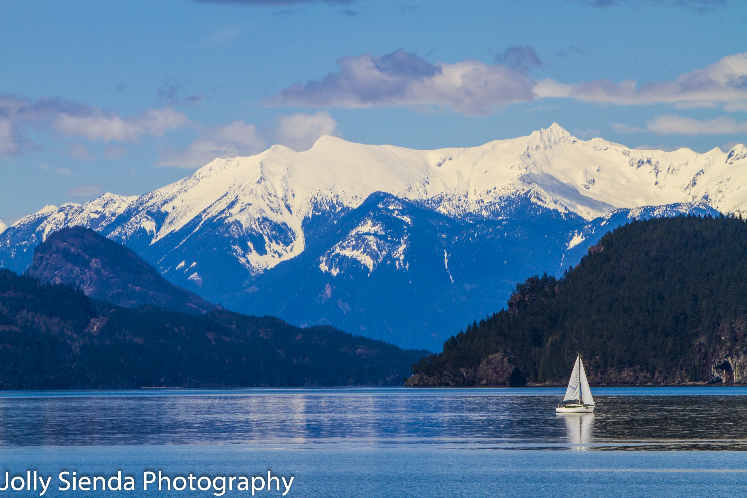 Sailboat on Harrison Lake and snow capped mountains