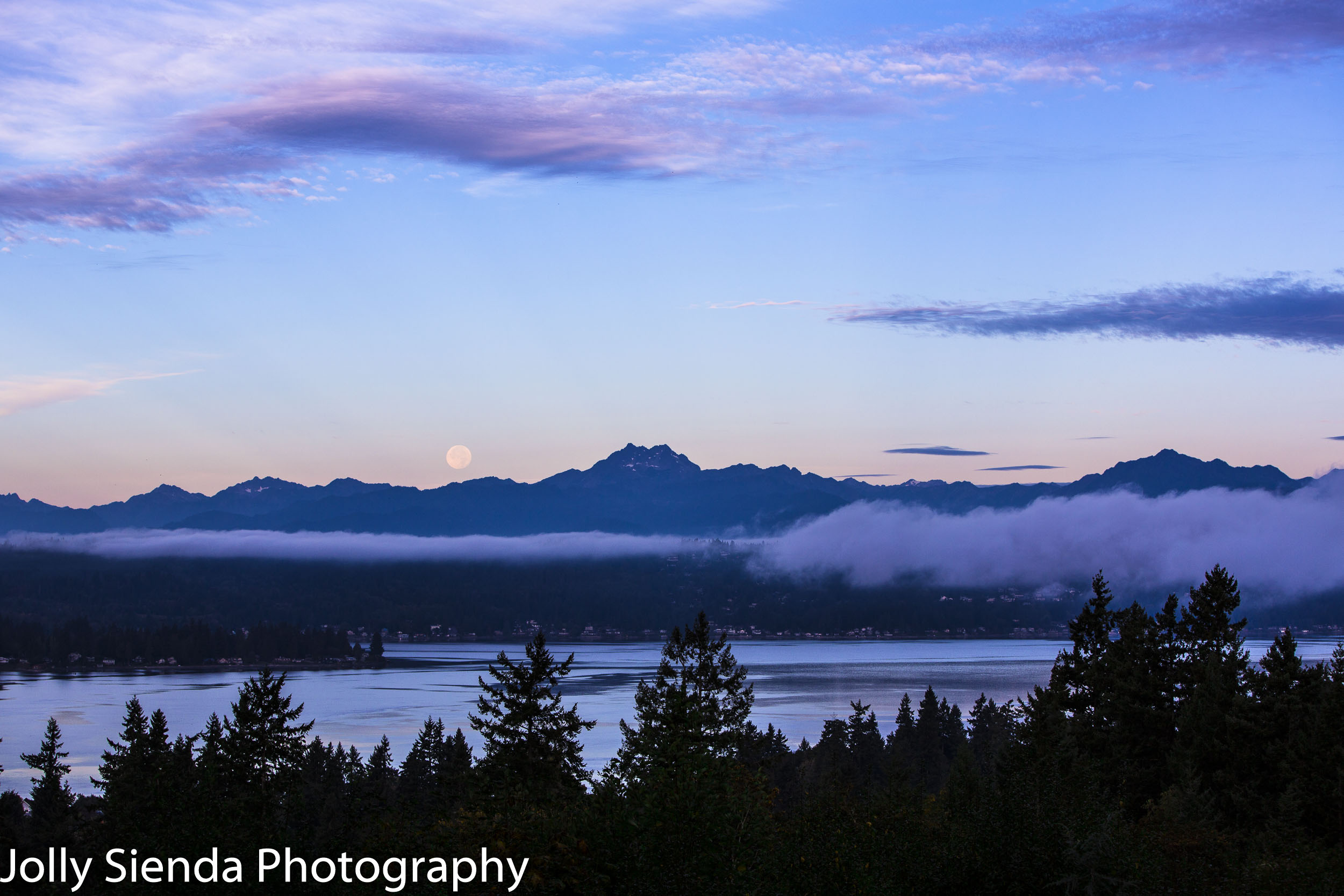Autumn full moon over Olympic Mountains with fog rising over the