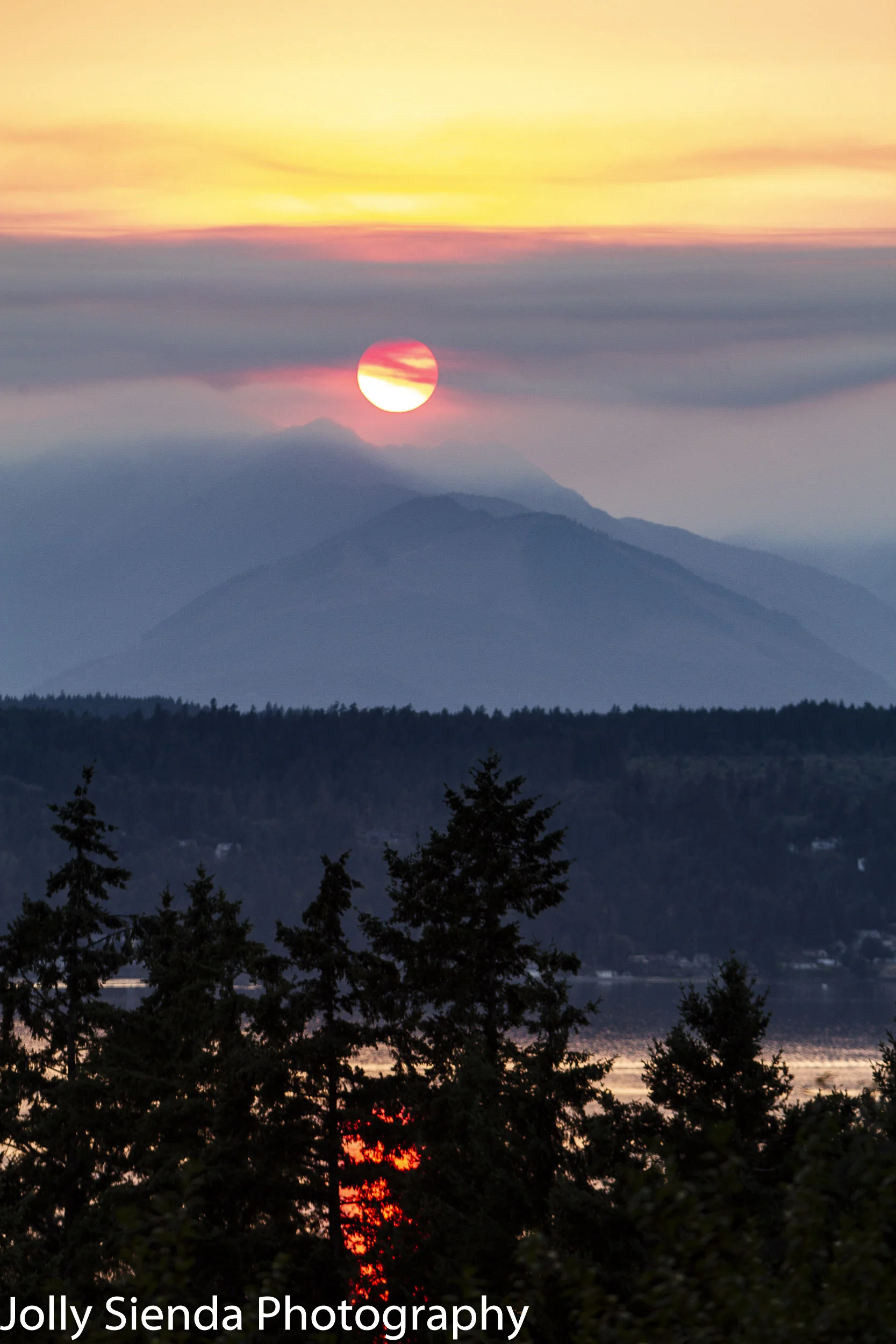 Smoke drifts past the sun and over the mountains