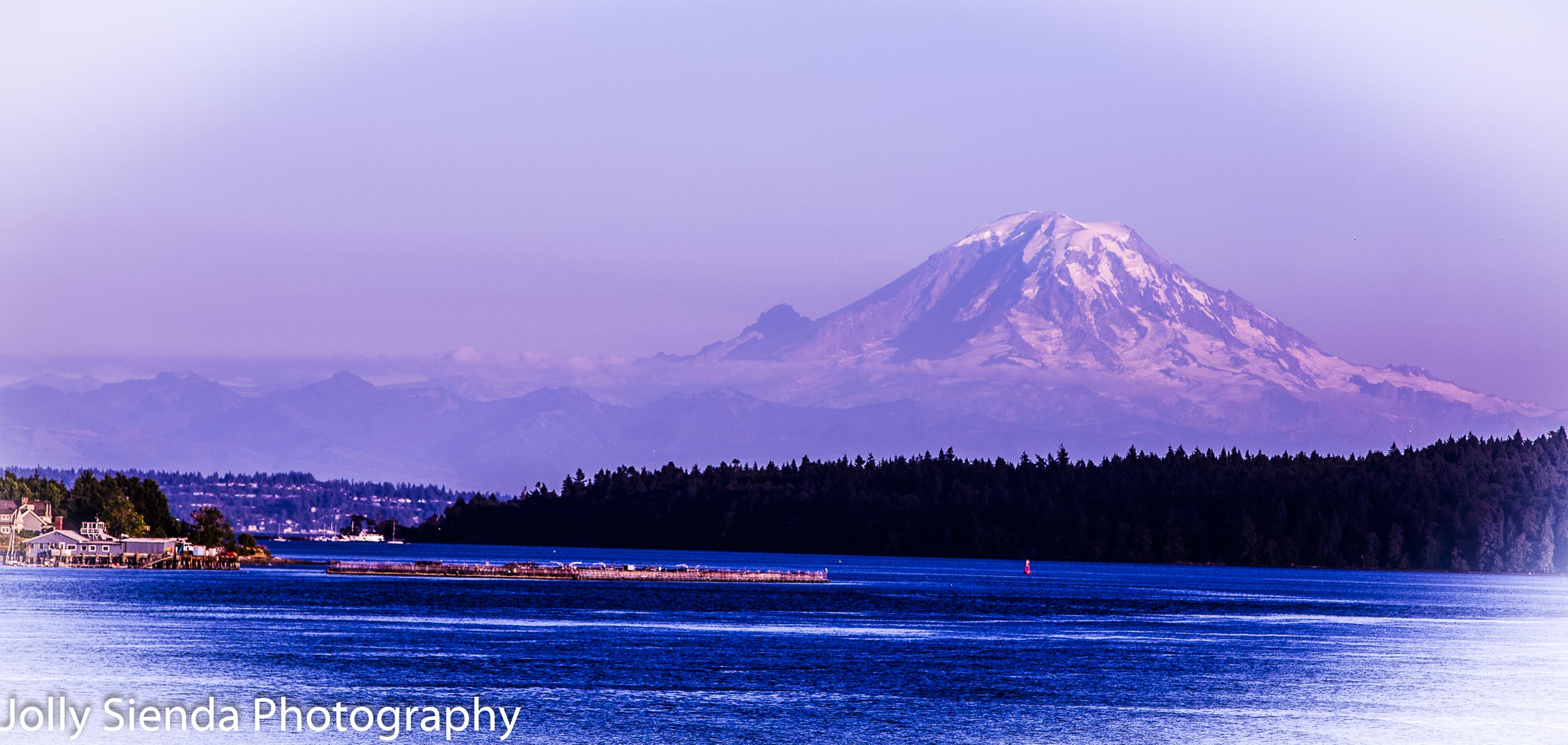 Mount Rainier at dusk towers over the Puget Sound during a pink 