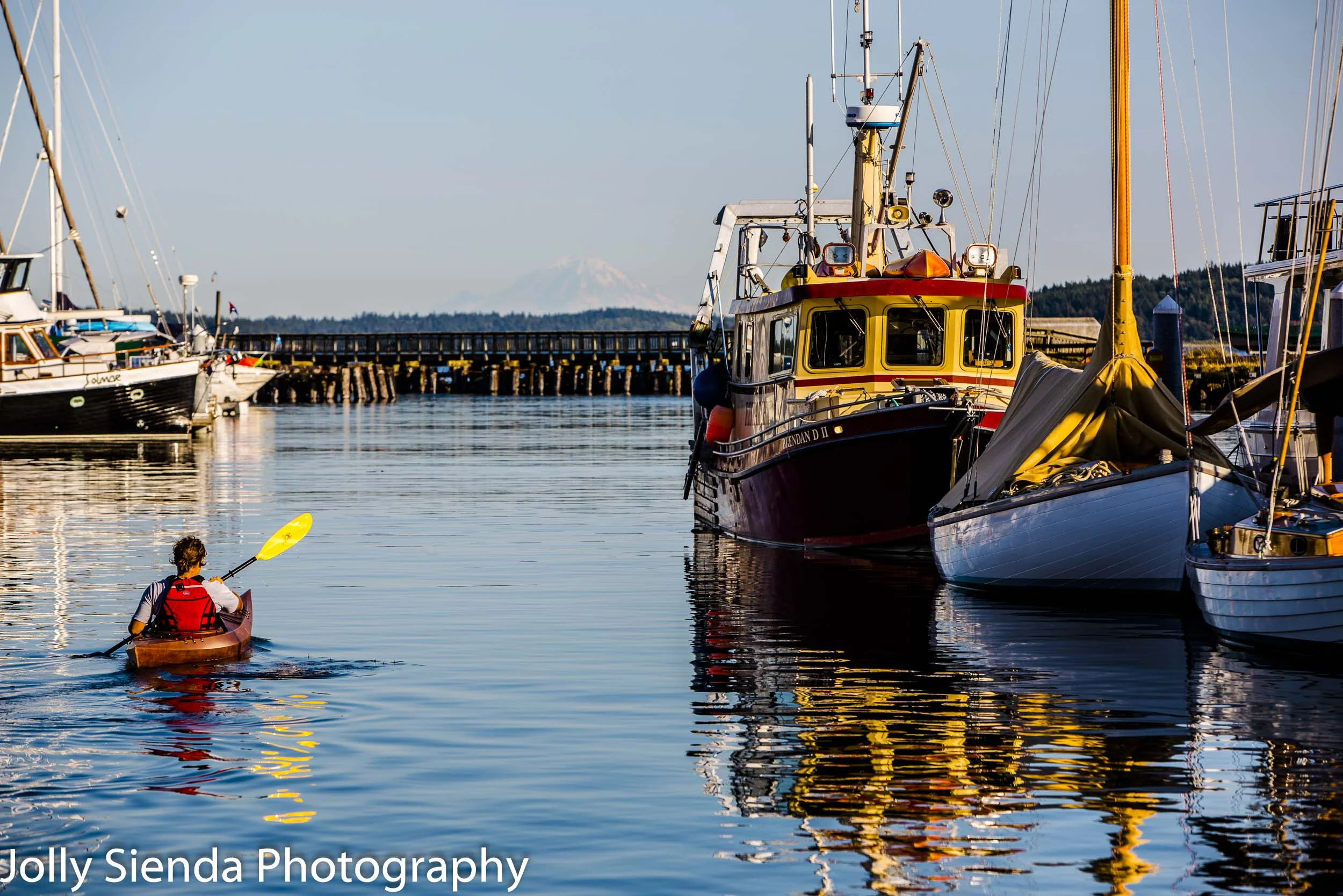 Woman in a canoe on the Puget Sound passes boats and sailboats w