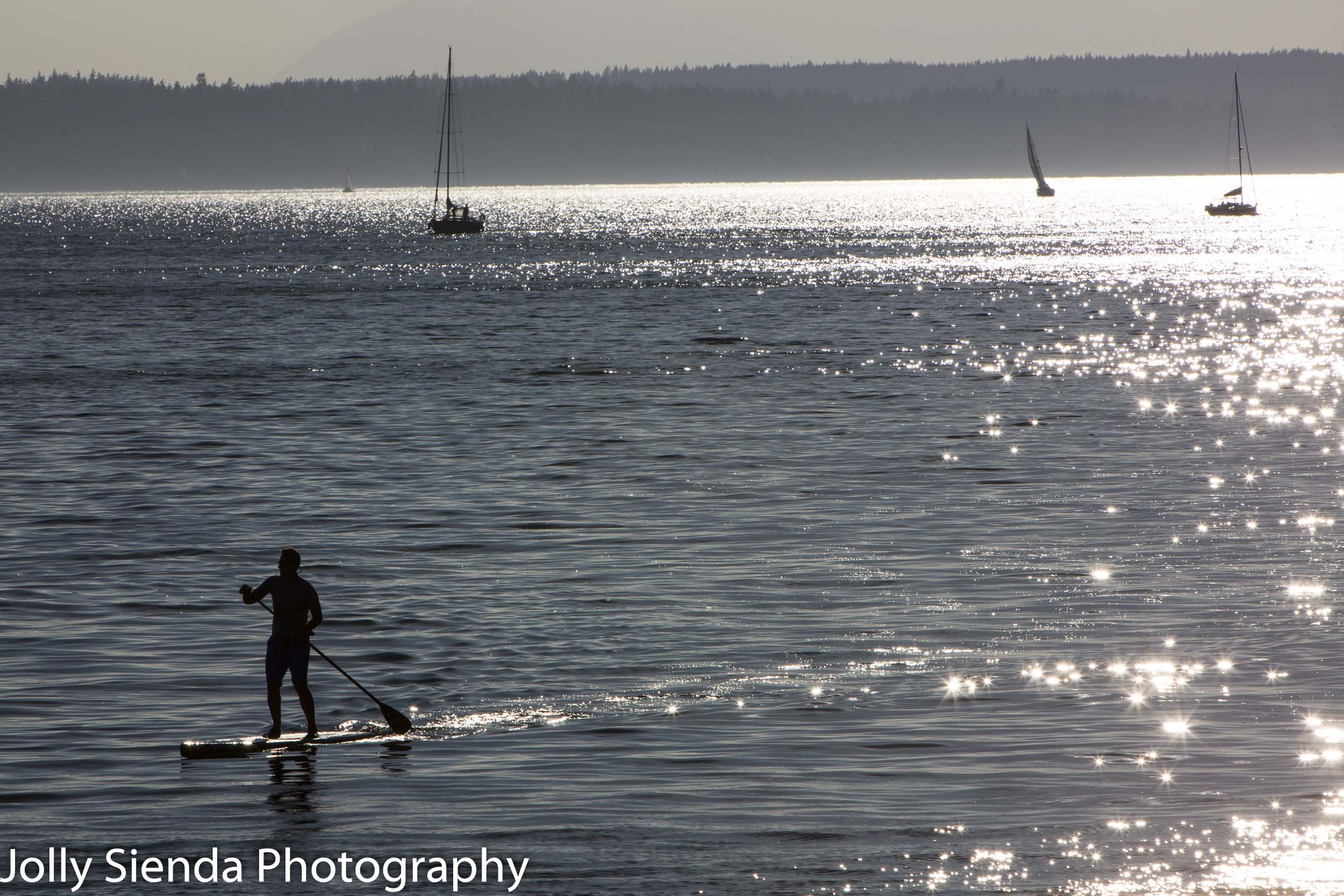 Paddle boarder and sailboats on the bay