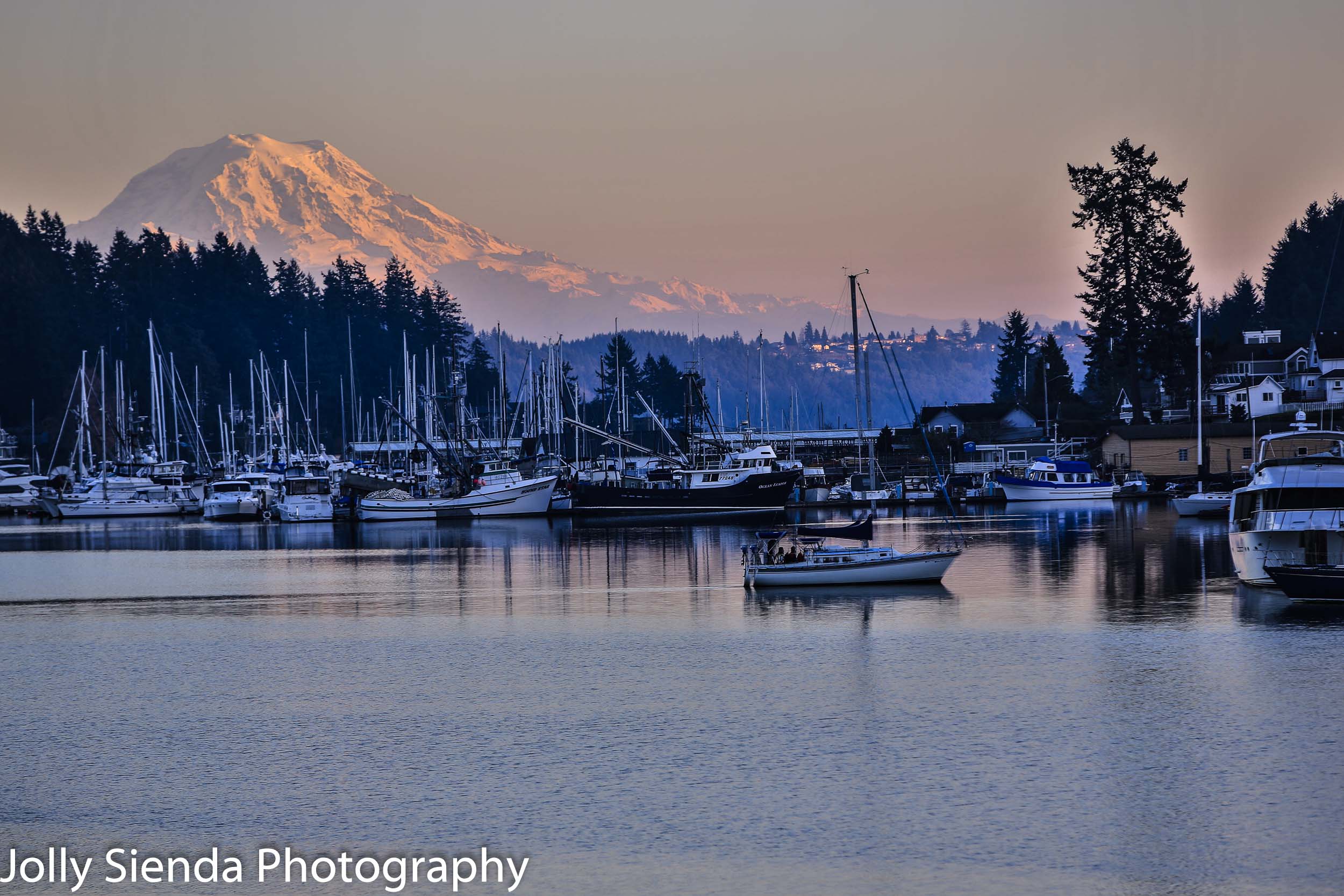 Sunset on Mount Rainier as a sailboat glides by in a marina