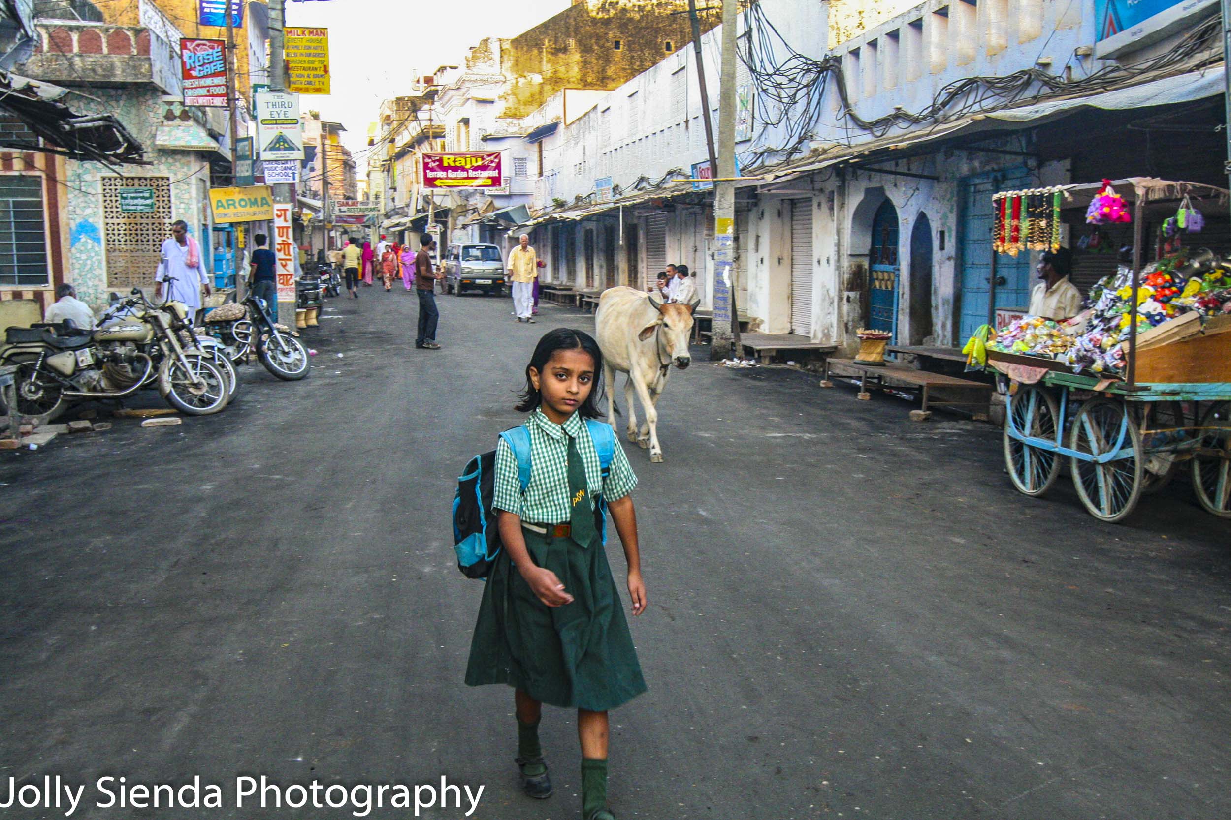 School girl in uniform walks down market street with a horned co