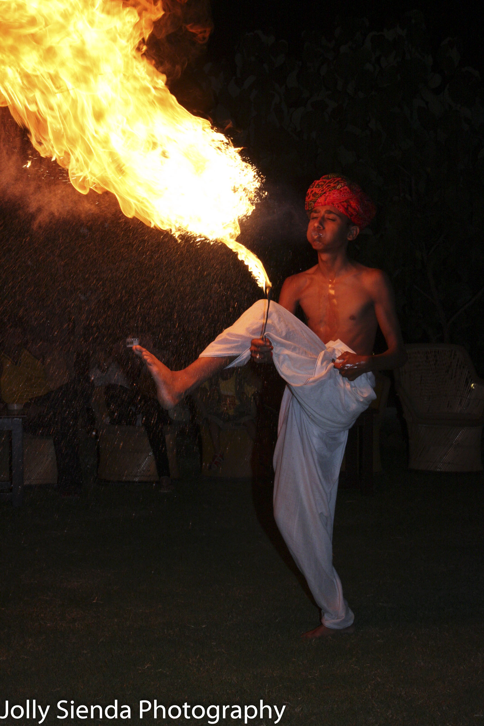 Man in the turban performing a dance with a large fire flame