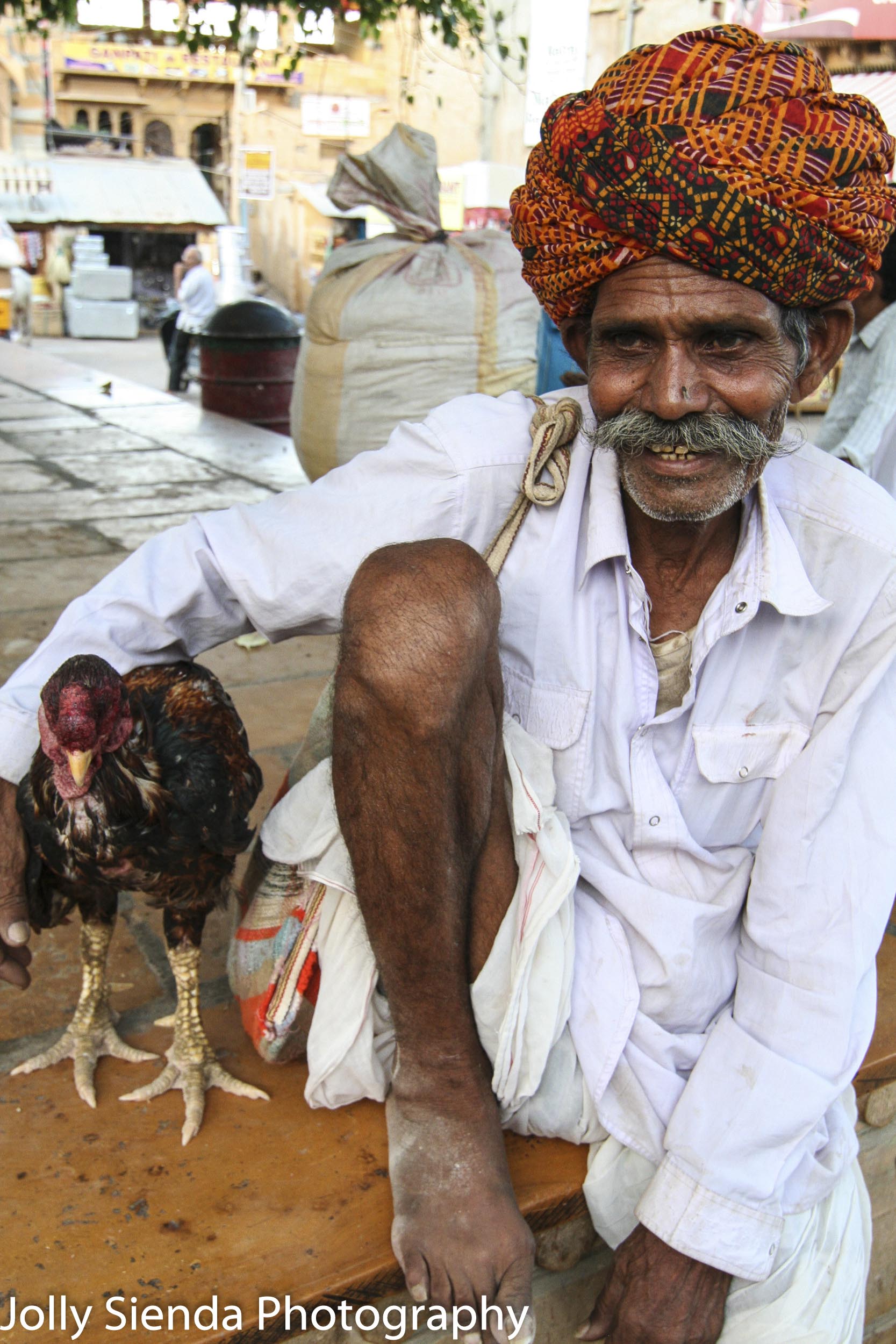 Chicken man wears a turban with his arm around his chicken