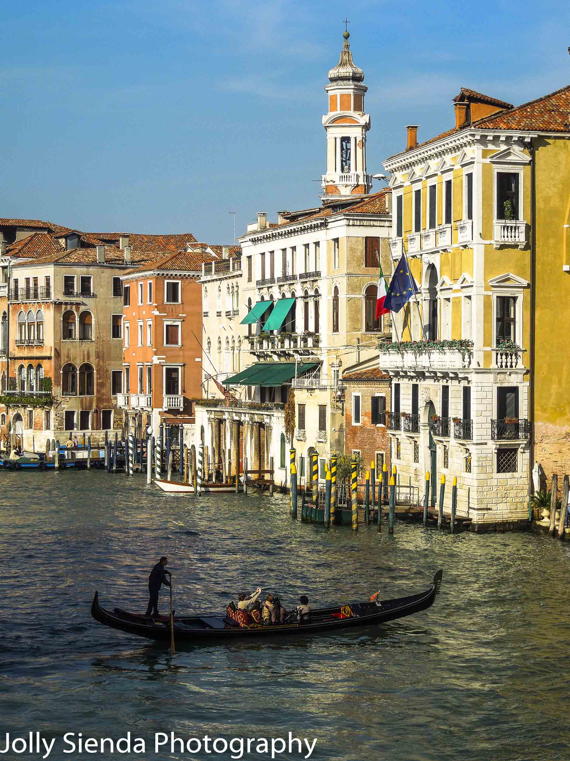 Gondolier uses his paddle to steer the gondola with tourists thr