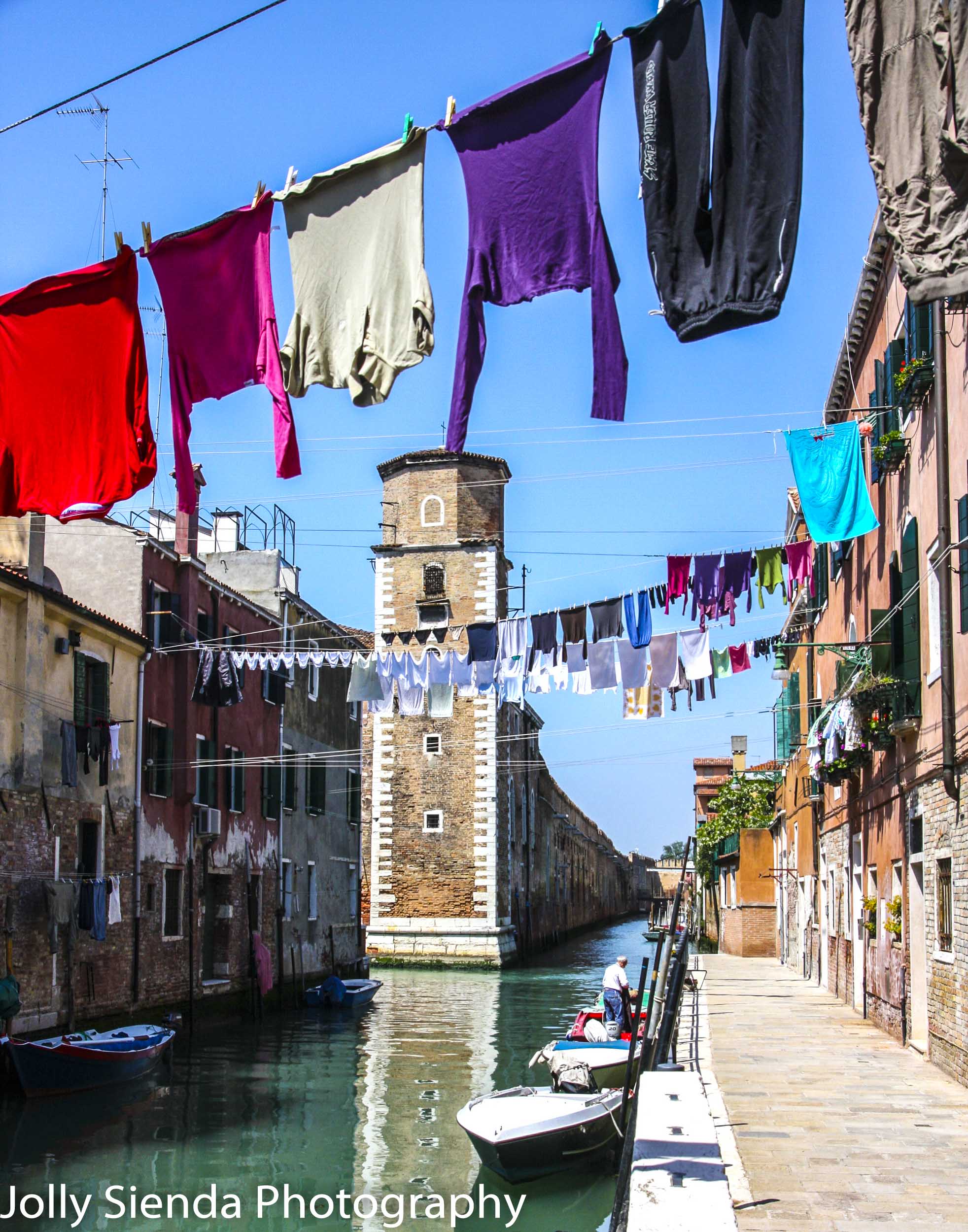 Quite Venetian canal with hanging laundry, boats, and a man in a