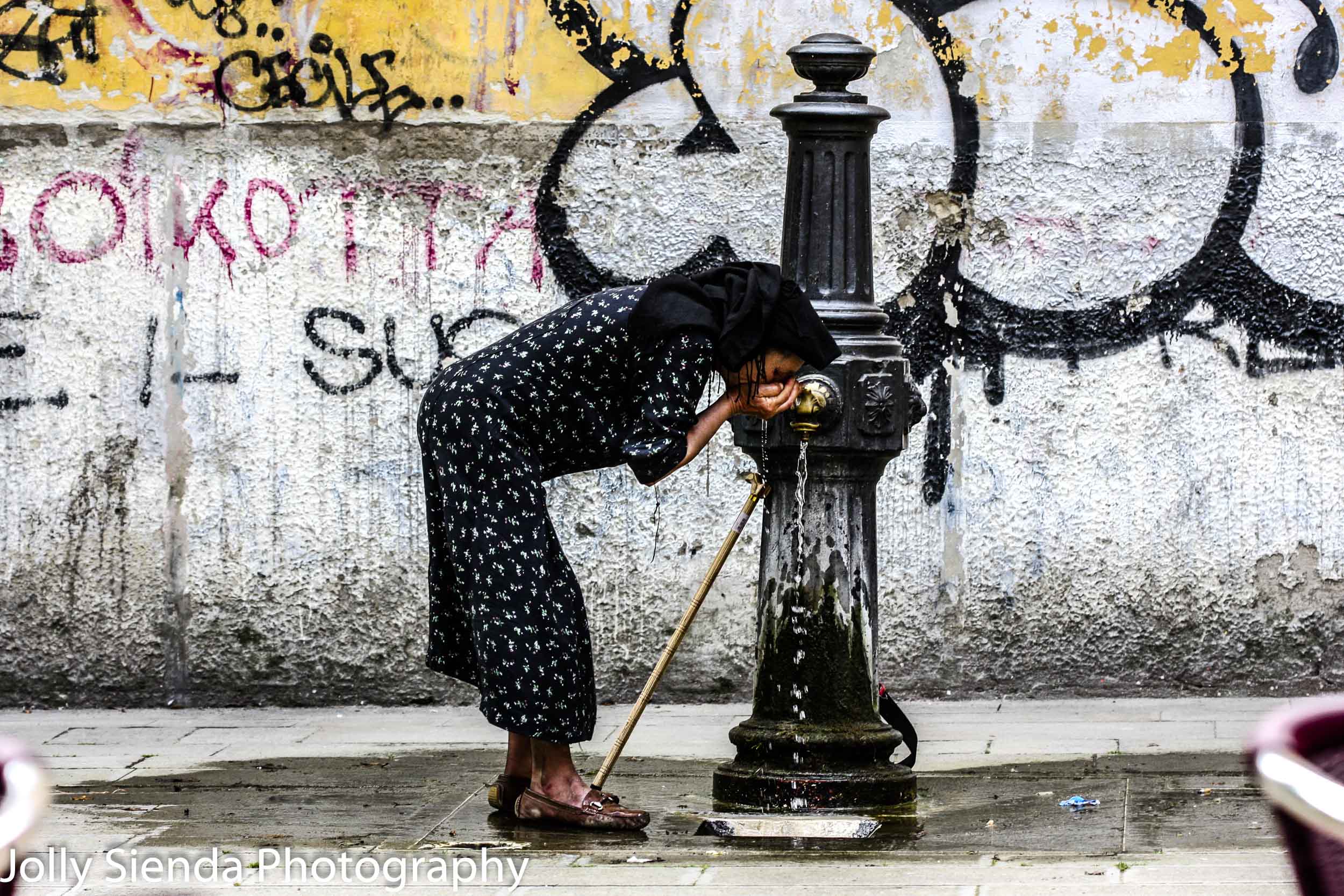 Venetian Gypsy Woman Drinks Water from her Hands over a  Fountai