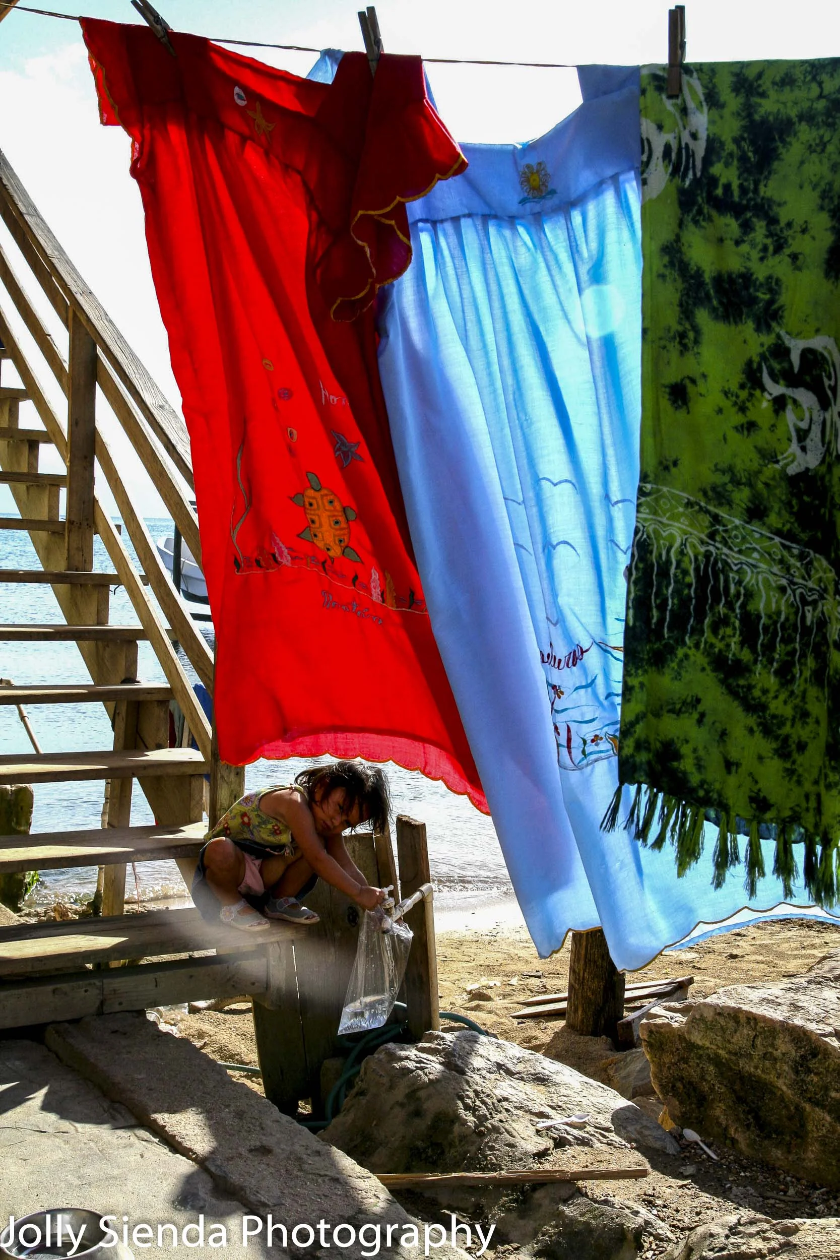 Child plays under hanging laundry