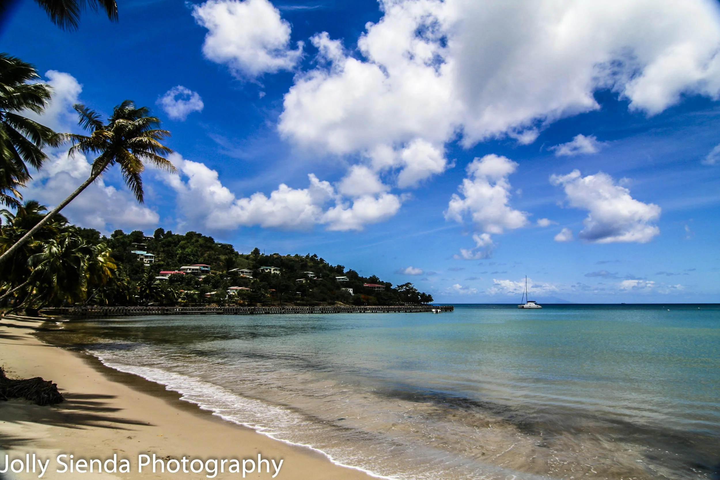 Deserted troplical beach, palm trees, and a sailboat 