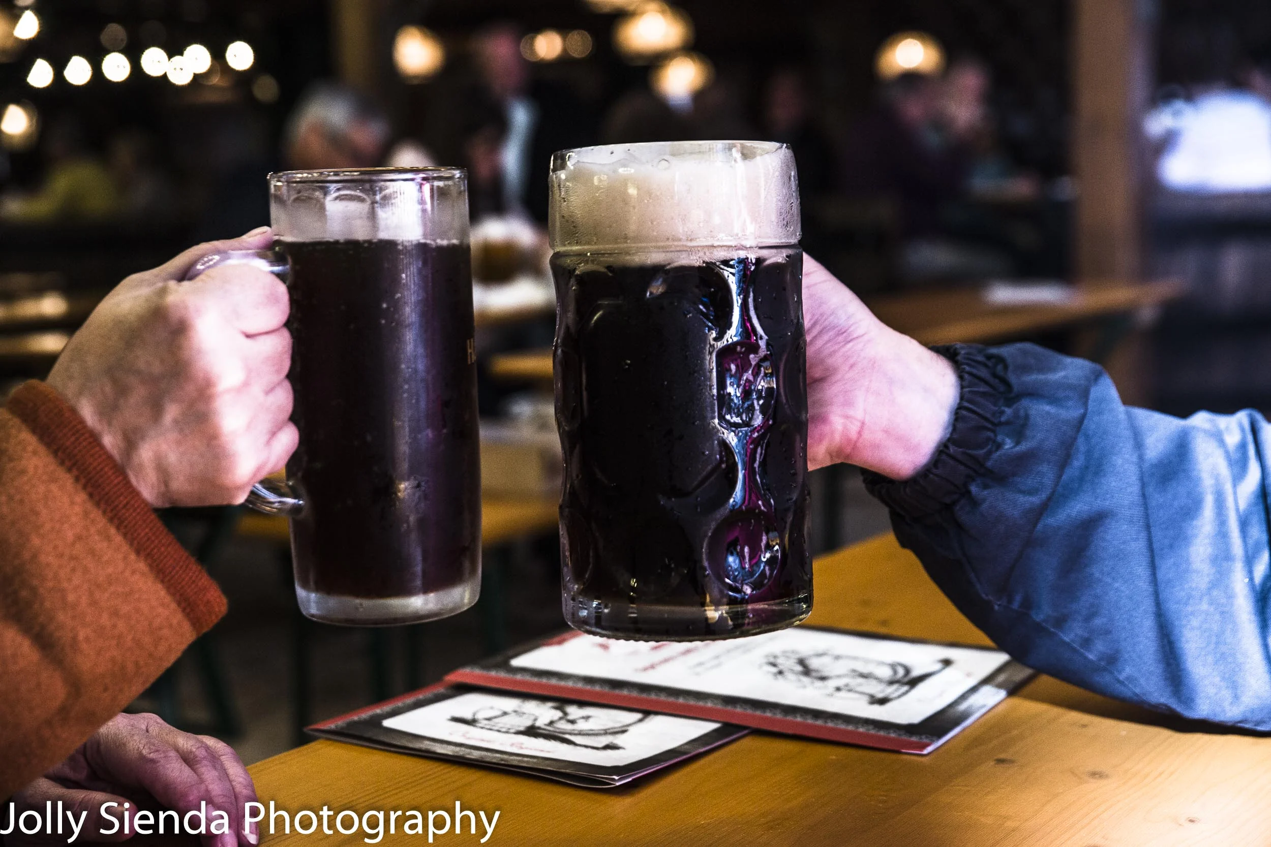 German prost with hands holding glass mugs of beer