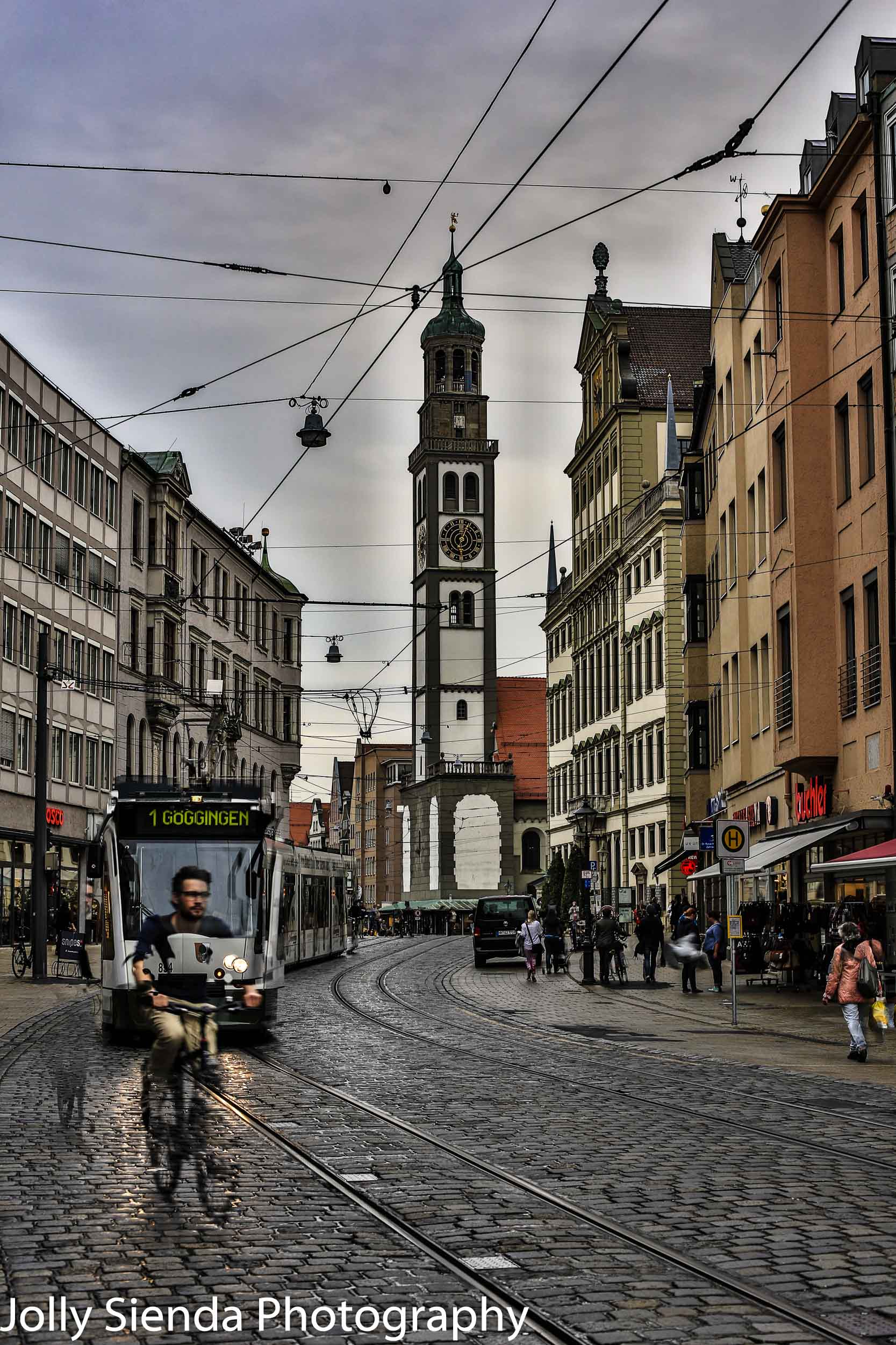 Bicyclist and cable car on cobblestone street