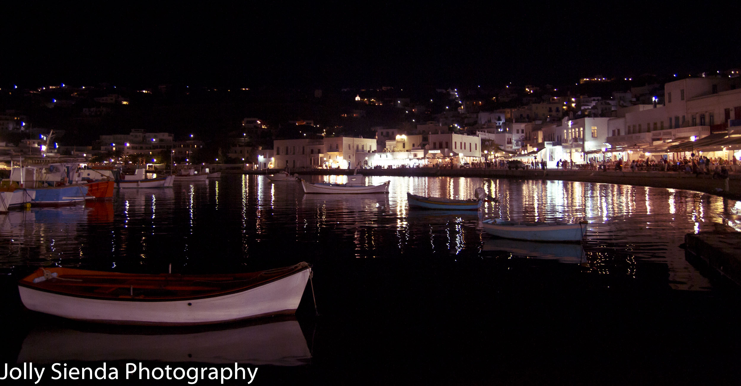 Boats and the town of Mykonos lit up at night